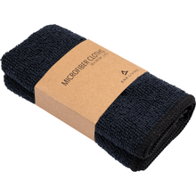 Een set van twee zwarte ENA Living microvezeldoeken (30x30 cm) van Abena Re-Seller GmbH, elk gevouwen met een bruin etiket met de tekst "Microfiber Cloths 30 x 30 cm" en een minimalistisch logo - ideaal voor gebruik als schoonmaakdoeken in het huishouden.