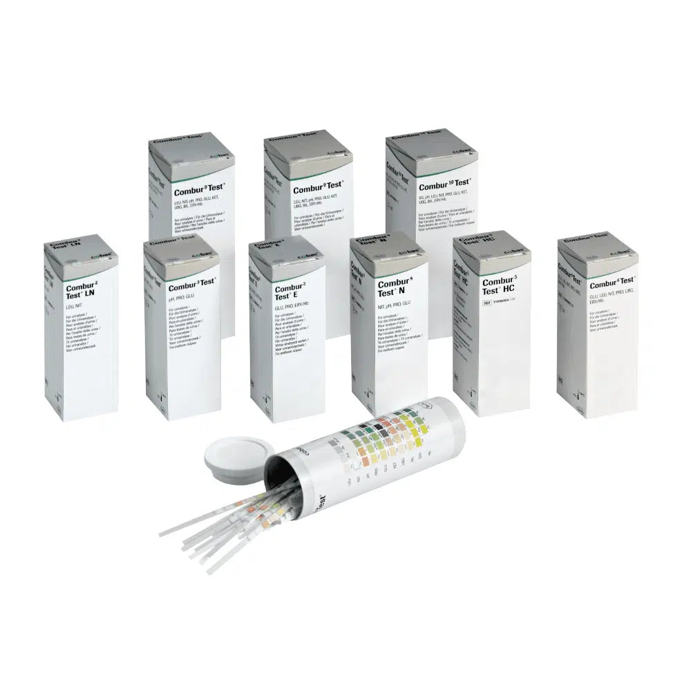 Achter een open cilindrische container met deksel verbergen zich negen dozen met het opschrift „Combur®“ van Servoprax GmbH, die elk 100 Roche urineteststrips bevatten. Aan de zijkant van de container is een meerkleurige tabel aangebracht, die perfect geschikt is voor het uitvoeren van een sneltest.