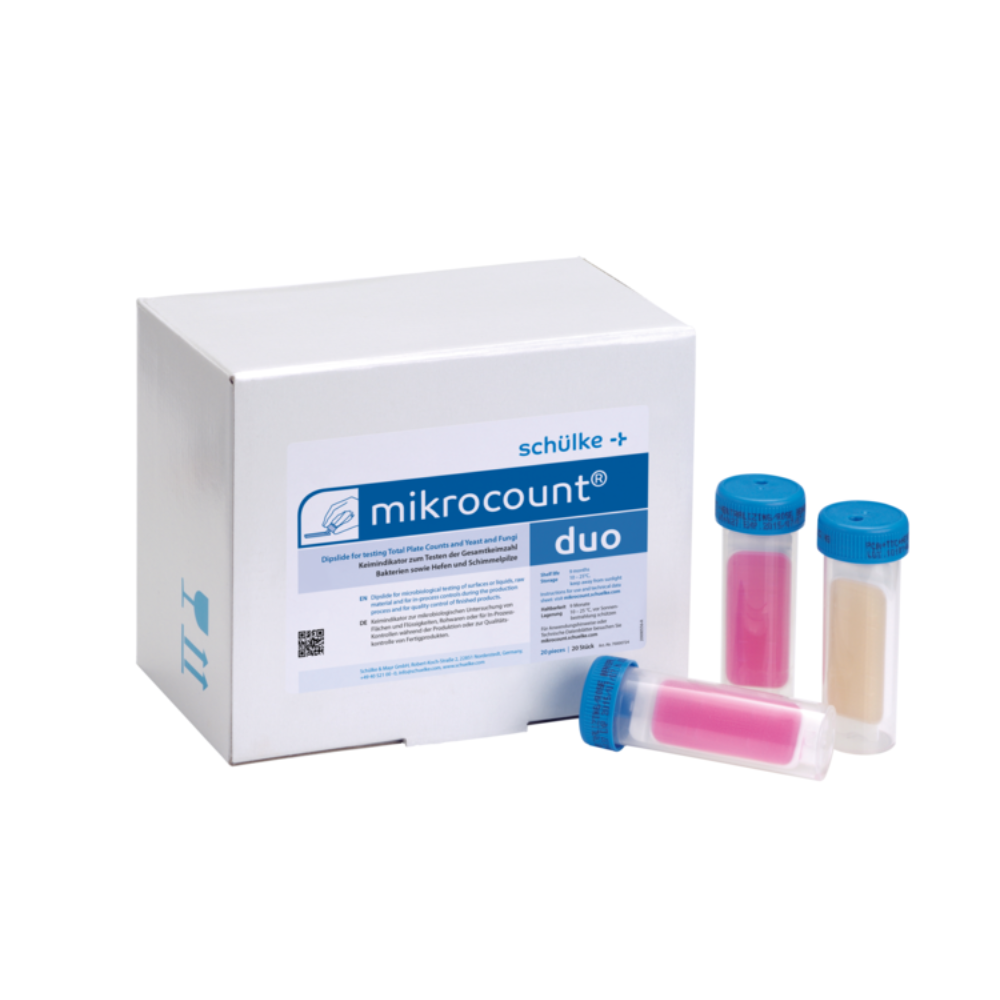 De afbeelding toont een doos met het opschrift „Schülke mikrocount® duo, kiemindicator | Verpakking (20 stuks)“ van het merk „Schülke & Mayr GmbH“ naast drie kleurgecodeerde buisjes met blauwe doppen. De buisjes bevatten roze en beige substanties die worden gebruikt voor het detecteren van micro-organismen op oppervlakken en in vloeistoffen, waaronder gisten en schimmels.