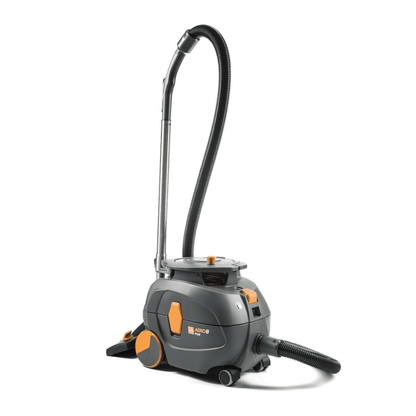 Een TASKI AERO 8 PLUS stofzuiger, geleverd door Diversey Deutschland GmbH & Co. OHG, in grijs en oranje, staat rechtop. Deze compacte en krachtige ketelstofzuiger beschikt over een lange flexibele slang en heeft een cilindrische behuizing met grote achterwielen en kleinere voorwielen voor uitstekende mobiliteit en efficiënte reiniging. Zijn werking wordt verbeterd door fluistertechnologie voor een stille werking.