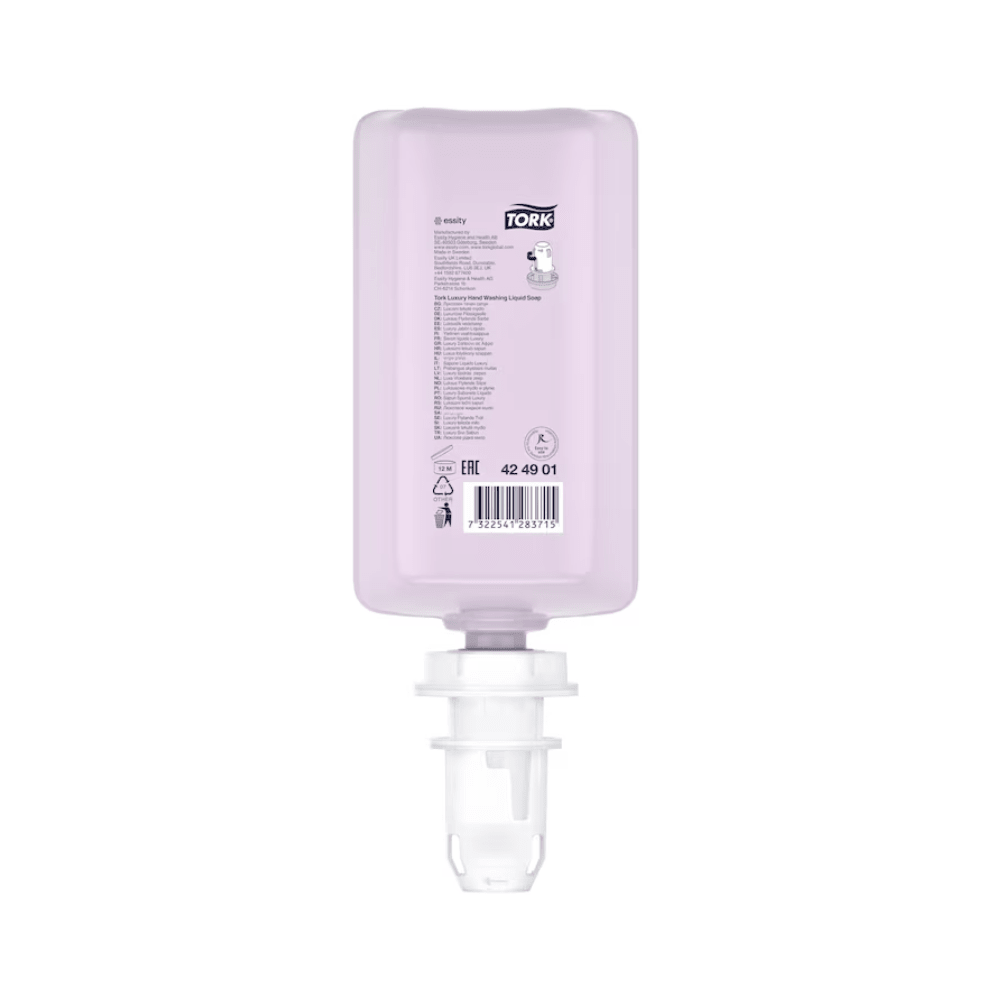 Een roze, rechthoekige fles Tork luxueuze vloeibare zeep met witte dop wordt tentoongesteld. Ze toont productdetails en een barcode en bevat luxueuze vloeibare zeep met natuurlijke ingrediënten, verrijkt met magnolia-extract. Deze navulling is ondersteboven gepositioneerd om eenvoudig in een dispenser te plaatsen en is onderdeel van een set van het merk TORK van Essity Professional Hygiene Germany GmbH.