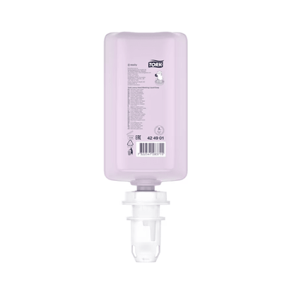 Een roze, rechthoekige fles Tork luxueuze vloeibare zeep met witte dop wordt tentoongesteld. Ze toont productdetails en een barcode en bevat luxueuze vloeibare zeep met natuurlijke ingrediënten, verrijkt met magnolia-extract. Deze navulling is ondersteboven gepositioneerd om eenvoudig in een dispenser te plaatsen en is onderdeel van een set van het merk TORK van Essity Professional Hygiene Germany GmbH.