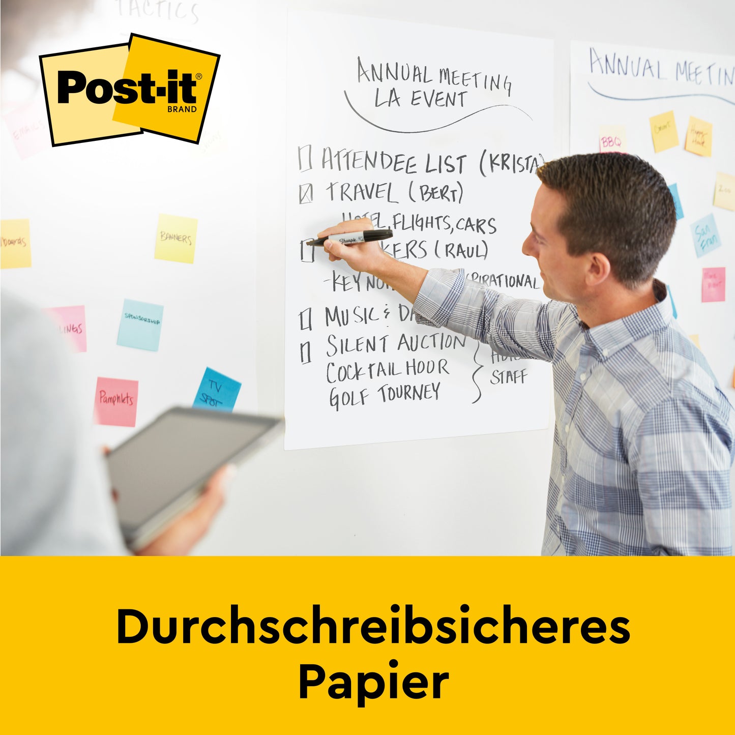 Ein Mann schreibt während einer Besprechung auf ein Post-it® Super Sticky selbsthaftendes Recycling Meeting Chart 559RP von 3M Deutschland GmbH (63,5x76,2 cm, 30 Blatt/Block), das im Hintergrund zu sehen ist; ein anderer hält ein Tablet. Text: "Durchschreibsicheres Papier.