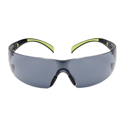 Die 3M™ SecureFit™ Schutzbrille 400 der 3M Deutschland GmbH zeichnet sich durch dunkel getönte, umlaufende Gläser und schwarze Rahmen mit grünen Akzenten an den Bügeln auf weißem Hintergrund aus.