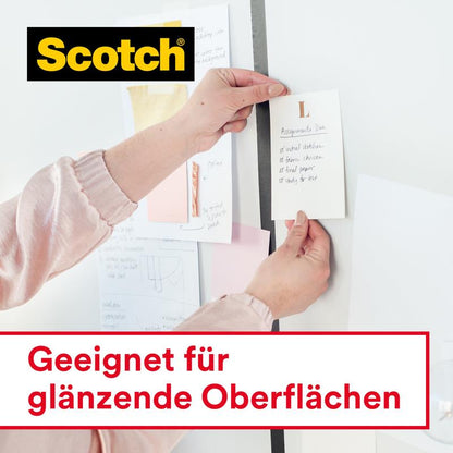 Een persoon bevestigt een briefje met verschillende papieren aan een muur met 3M Deutschland GmbH Scotch® Crystal plakband, transparant, voordeelverpakking (8 rollen, 19 mm x 33 m). Tekst: "Geschikt voor glanzende oppervlakken".