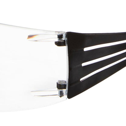 Close-up van de 3M™ SecureFit™ leesbeschermingsbril van 3M Deutschland GmbH. Deze toont de heldere lens en de zwarte poot met drie parallelle sleuven en het zichtbare scharnier dat de poot met de lens verbindt.