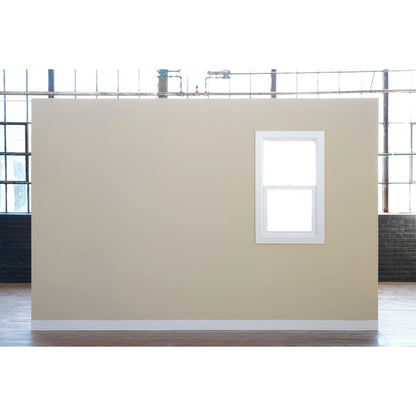 Een beige binnenmuur, beplakt met 3M Deutschland GmbH Scotch® Afplaktape Classic (48 mm x 50 m, 1 rol/verpakking, 70% PEFC), toont een wit omlijst raam, een houten vloer en blootliggende leidingen voor grote industriële ramen.