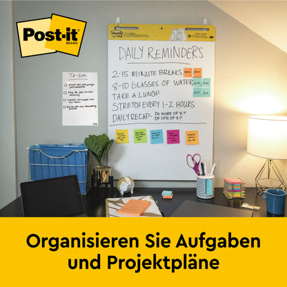 Ein Arbeitsbereich mit Stuhl, Schreibtisch, Zubehör und einer Wandtafel - ideal für die Organisation von Aufgaben und Projektplänen mit dem umweltfreundlichen Post-it® Super Sticky selbsthaftendes Recycling Meeting Chart 559RP (63,5x76,2 cm, 30 Blatt/Block).