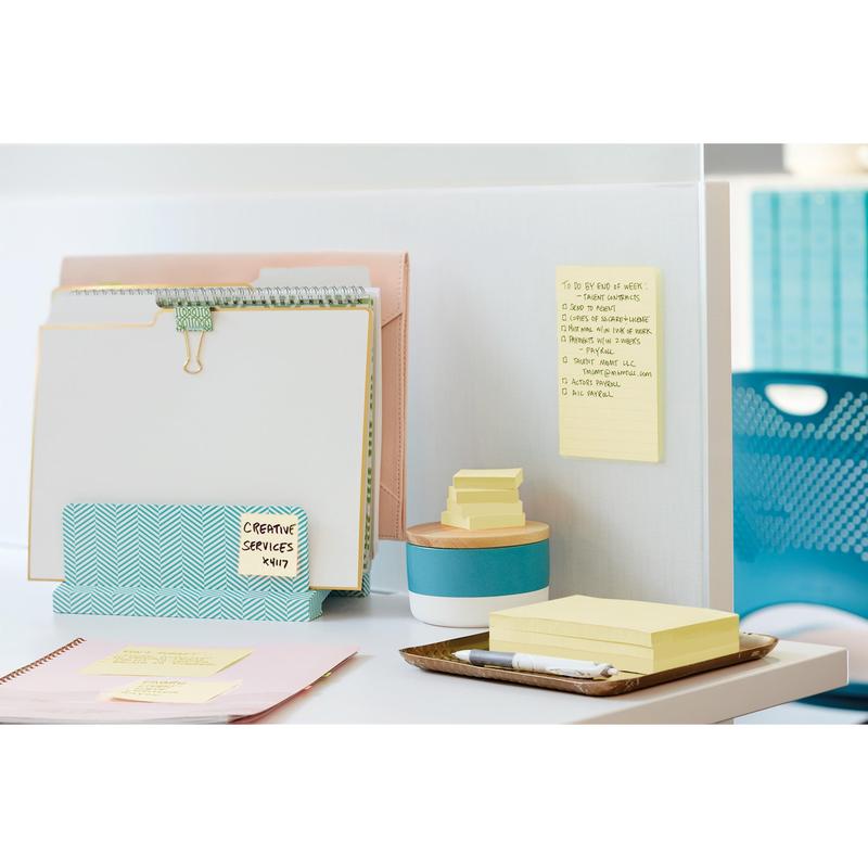 Op een opgeruimd bureautafel staat de Post-it® Z-Notes Dispenser PRO van 3M Nederland B.V. in zwart met gele Post-it® Super Sticky Z-Notes (76x76 mm, 90 vellen), samen met ordners, een pen, een houder met houten deksel en een blauwe stoel.