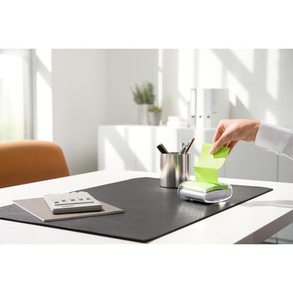 Een persoon trekt een gele Post-it® Super Sticky Z-Note (76 x 76 mm) uit de zwarte PRO Post-it® Z-Notes Dispenser van 3M Deutschland GmbH, op een opgeruimd bureau met rekenmachine, pennenhouder en zwarte onderlegger bij helder daglicht.