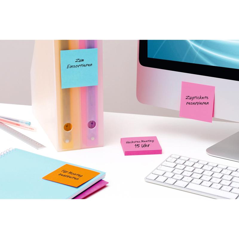 Een bureauscène met pastelkleurige ordners, notitieboeken en 3M Post-it® Notes Geel (76x76 mm, 90 vel/blok, 6 blokken, 100% PEFC), die aan kantoormateriaal en een monitor zijn bevestigd, naast een wit toetsenbord en een blauw scherm.