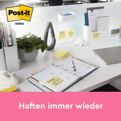 Een opgeruimd bureau met planner, laptop, plant en kantoorbenodigdheden zoals 3M Deutschland GmbH Post-it® Notes (Geel, 76x127 mm, 100 vel/blok), met gele notities op de scheidingswand. Boven een roze balk aan de onderkant staat "Hechten steeds opnieuw".