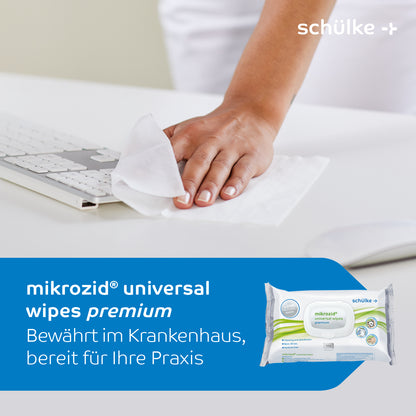 Een persoon gebruikt Schülke Mikrozid® universal wipes desinfectiedoekjes premium om een wit toetsenbord schoon te maken. De tekst luidt: 'Schülke Mikrozid® universal wipes desinfectiedoekjes premium. Beproefd in het ziekenhuis, klaar voor uw praktijk.' In het onderste deel van de afbeelding is de productverpakking afgebeeld, die de effectiviteit voor snelle desinfectie van medische oppervlakken benadrukt.